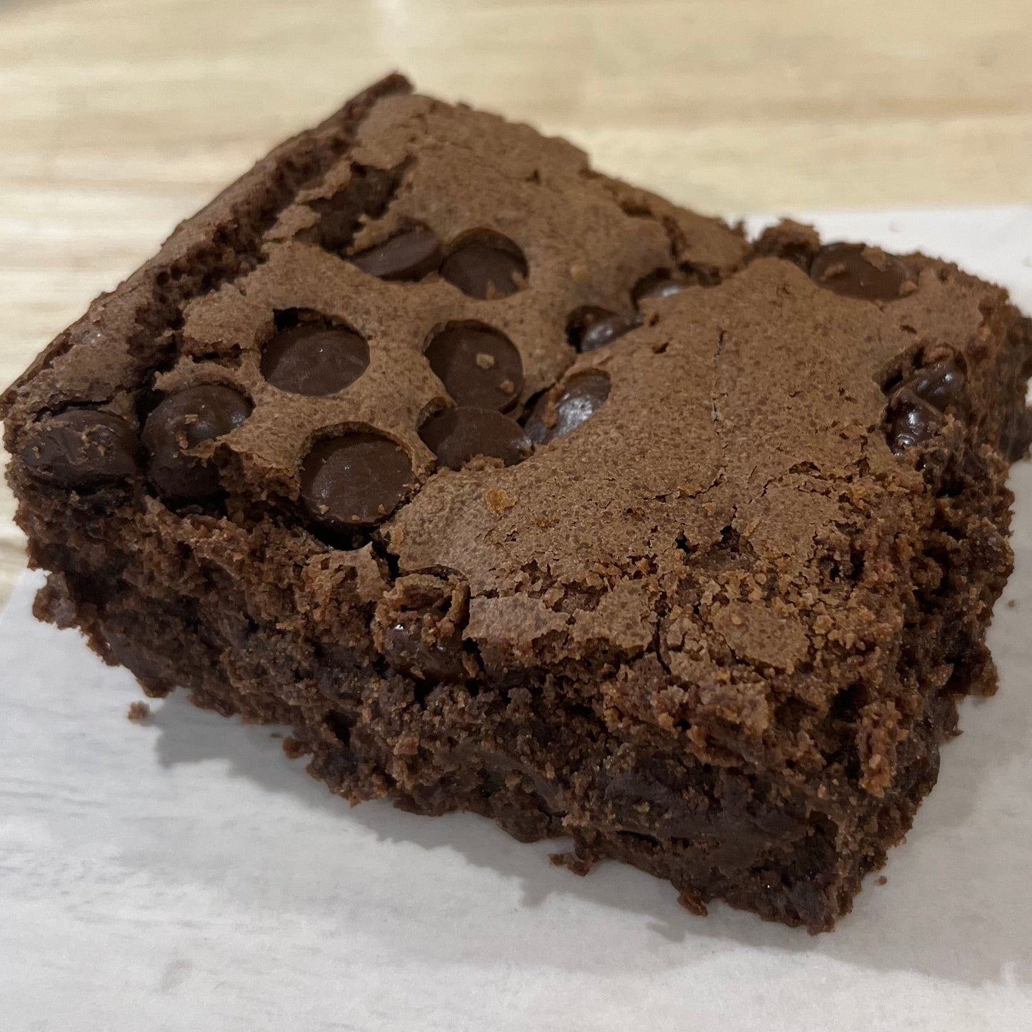 Chocolate brownie with chocolate chips on a white paper towel