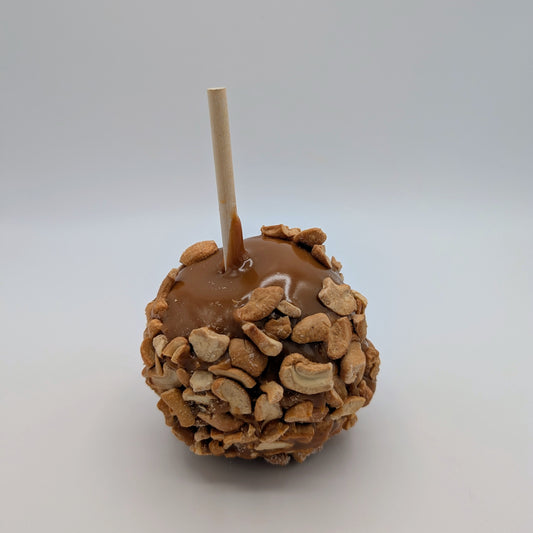 Caramel apple with cashew nuts on a white background