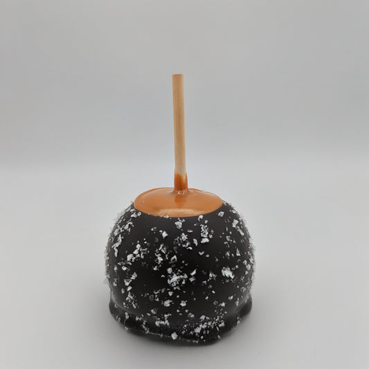 Caramel apple with dark chocolate ans sea salt coating on a gray background