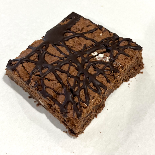 Chocolate brownie with a drizzle of chocolate on a white background